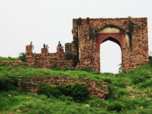 Three boys sit astride ancient ruins at Futehpur Sikri.