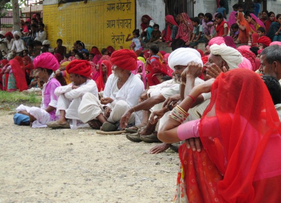 Men - most of them in brilliant turbans - sit and watch a performance in a village square near Ranakpur, Rajasthan.