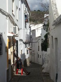 And old man rests in a sunny spot on a narrow street in Casares.